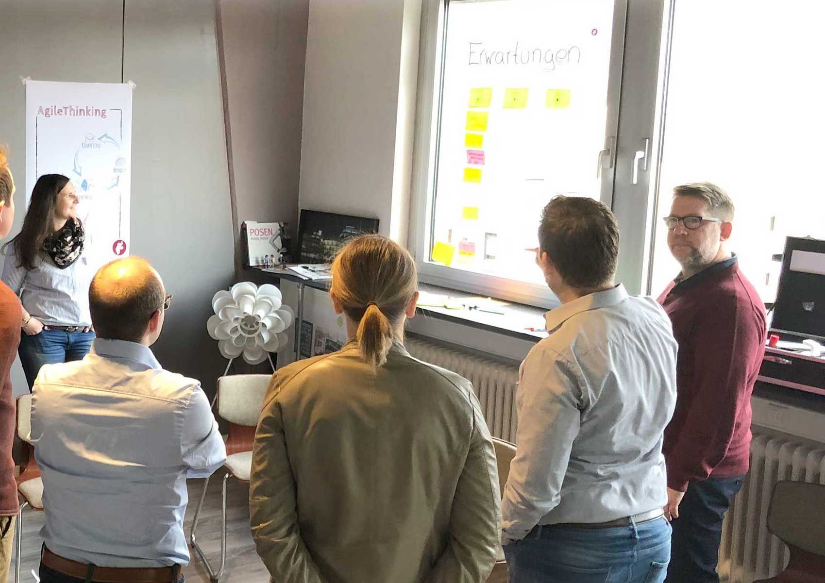 Im kleinen Kreis in einem Büro diskutieren mehrere Menschen (Agile Organisationsberatung)